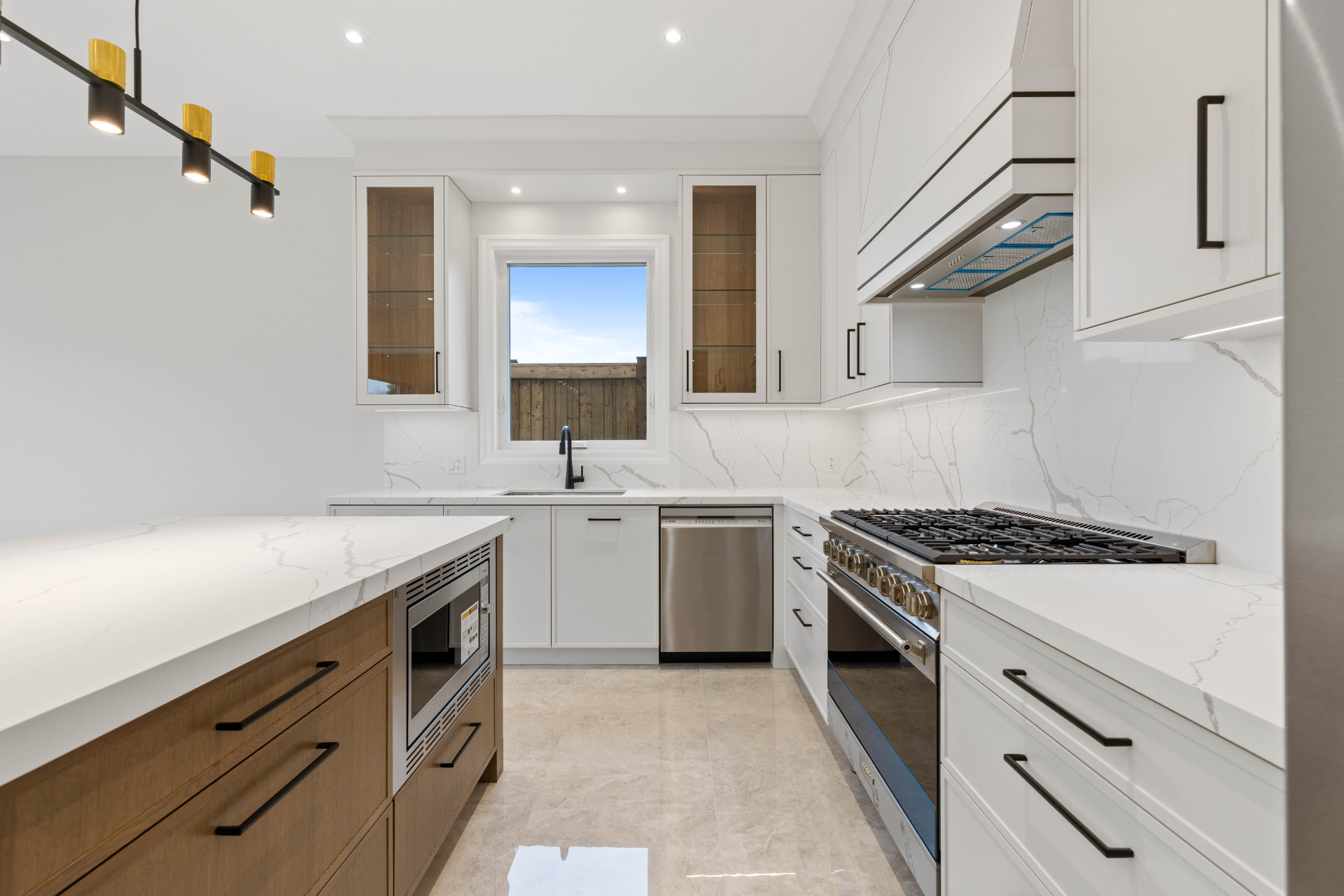 Kitchen range wall with marble backsplash, custom hood and gas cooktop