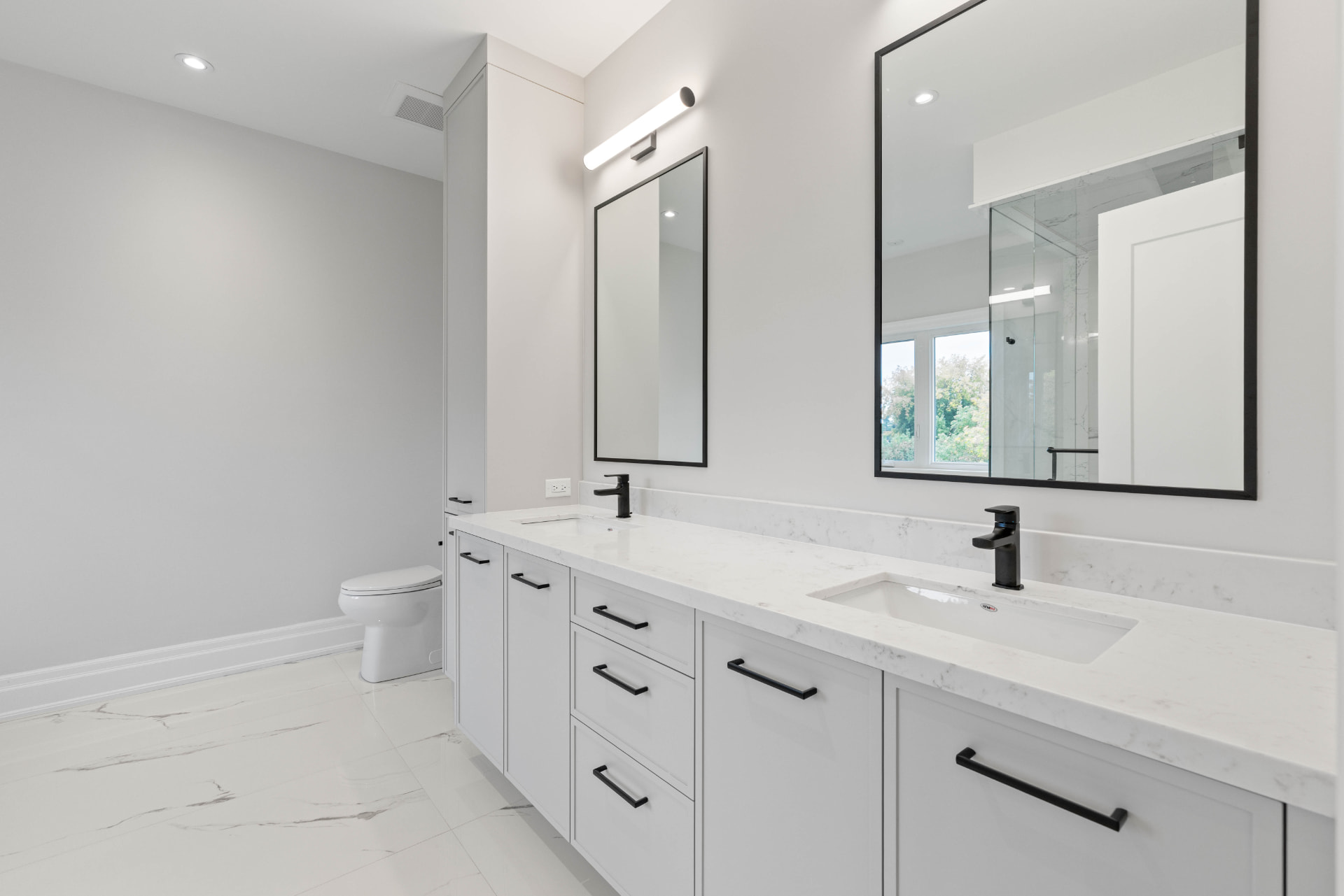 Ensuite double vanity with white cabinetry, marble counters and black fixtures