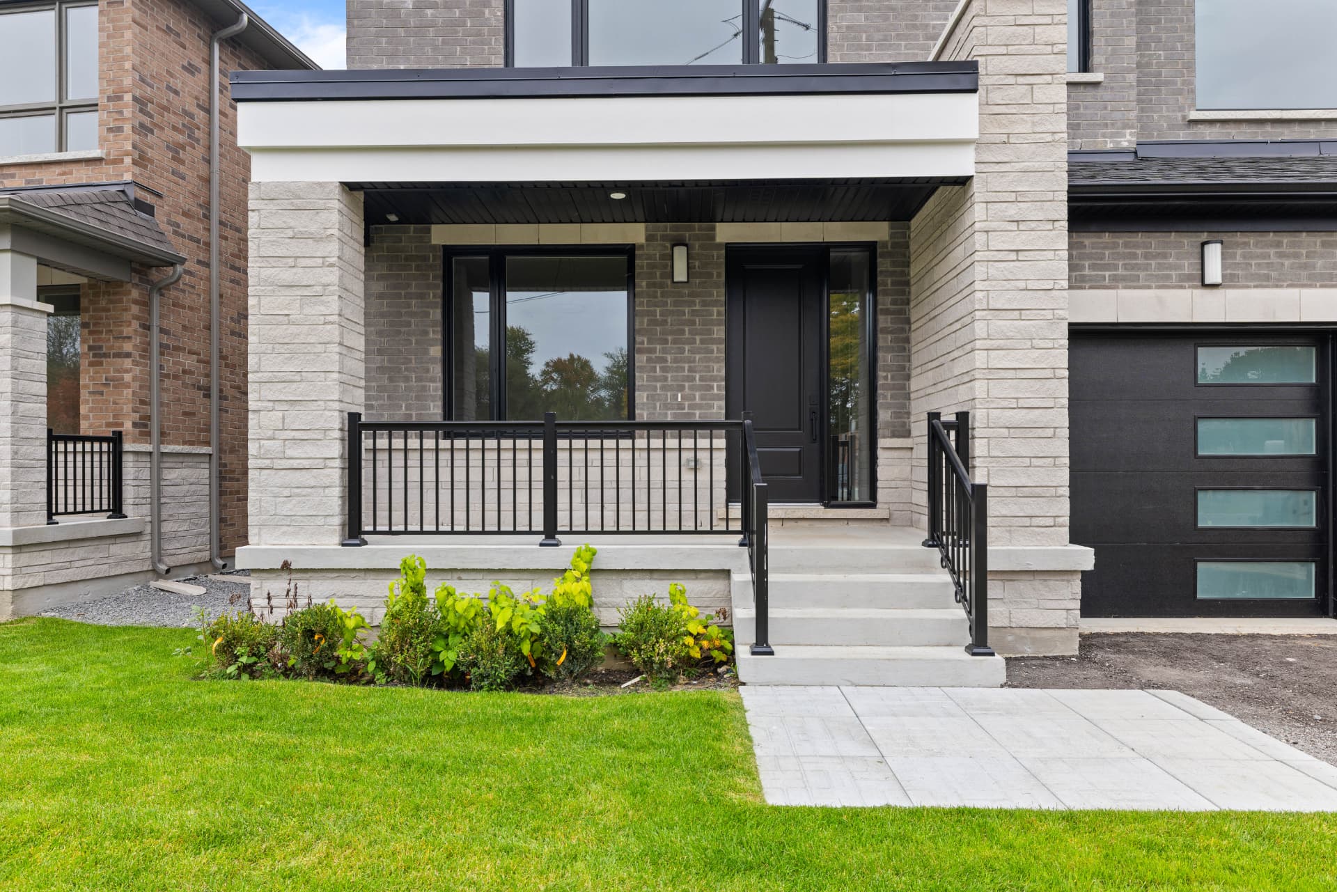 Covered front porch with stone columns, iron railings and glazed entry door