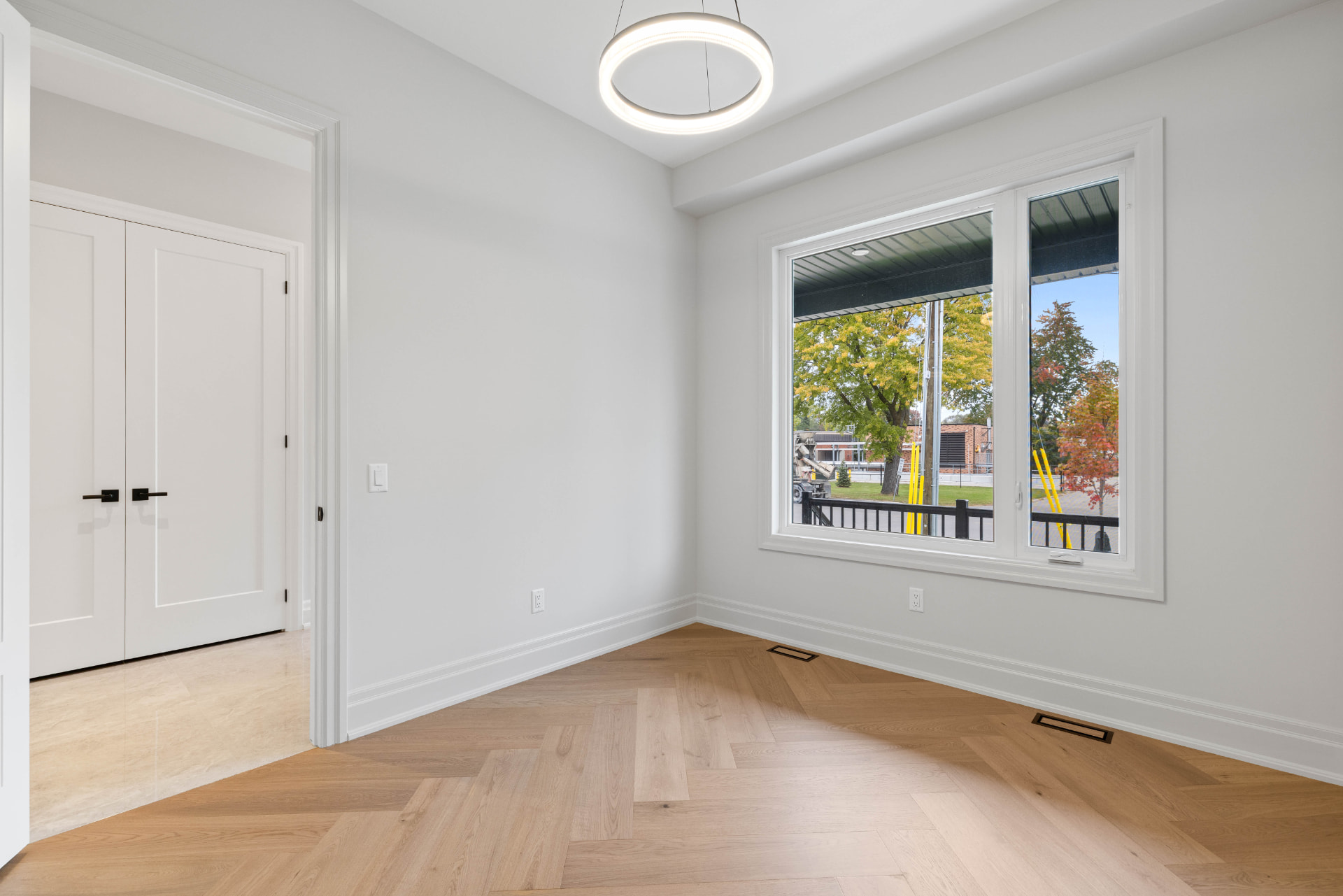 Second bedroom with ring chandelier, double closet doors and herringbone oak floors