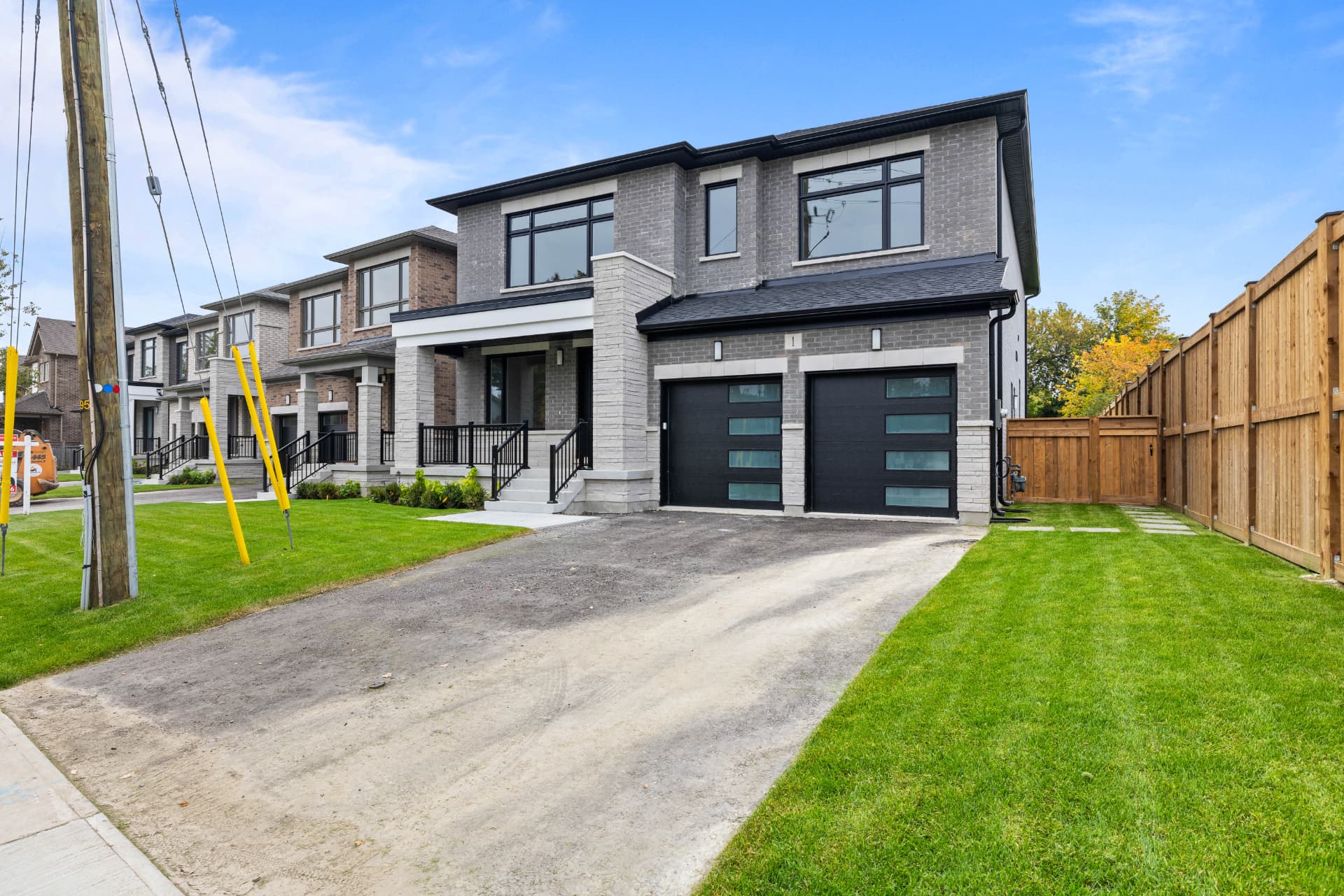 Corner view of the home with double garage, driveway and fenced side yard