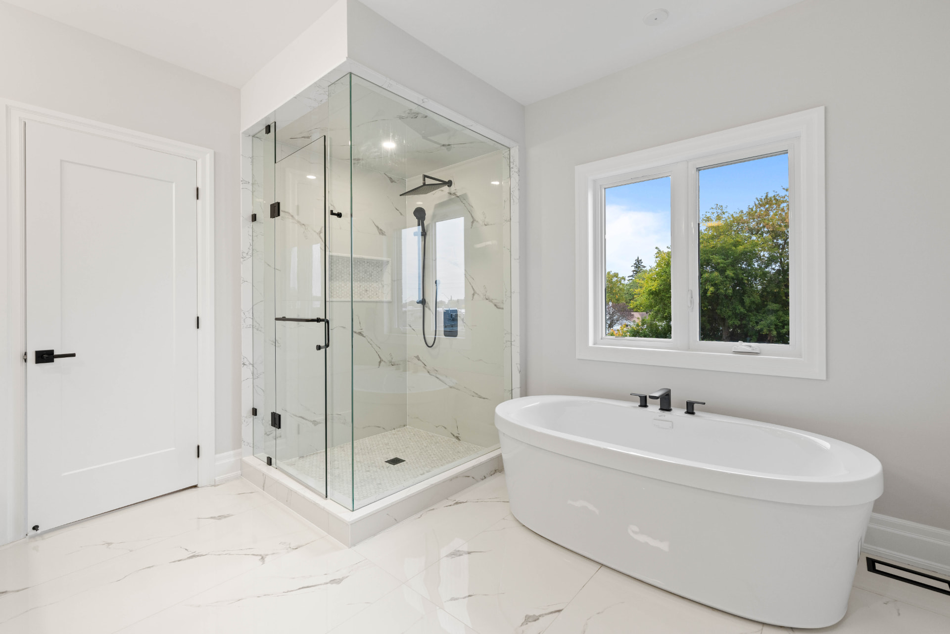 Ensuite with glass shower, freestanding soaker tub and marble-look tile