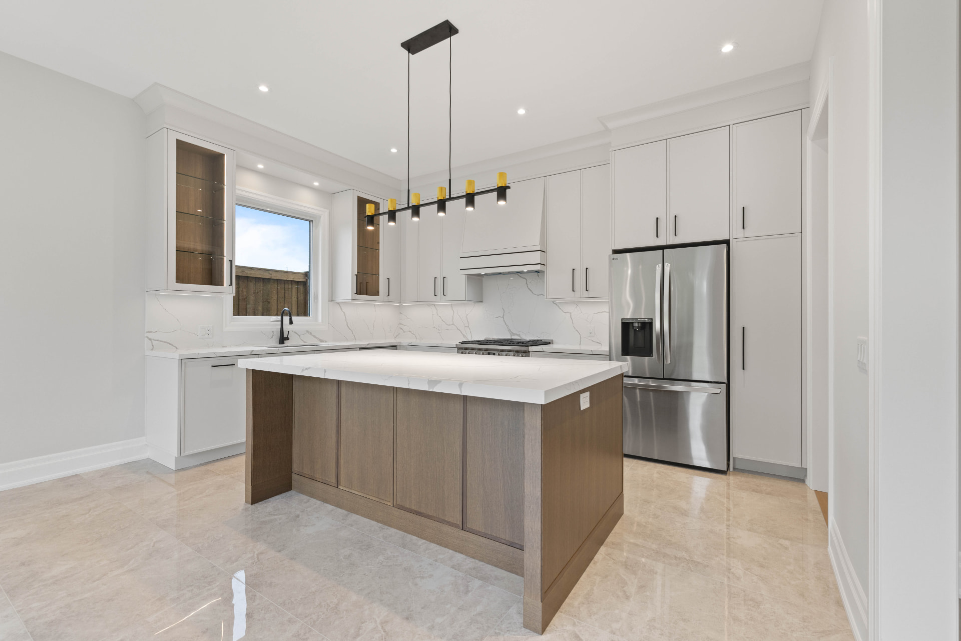 Kitchen island in greige oak with quartz counters and linear pendants